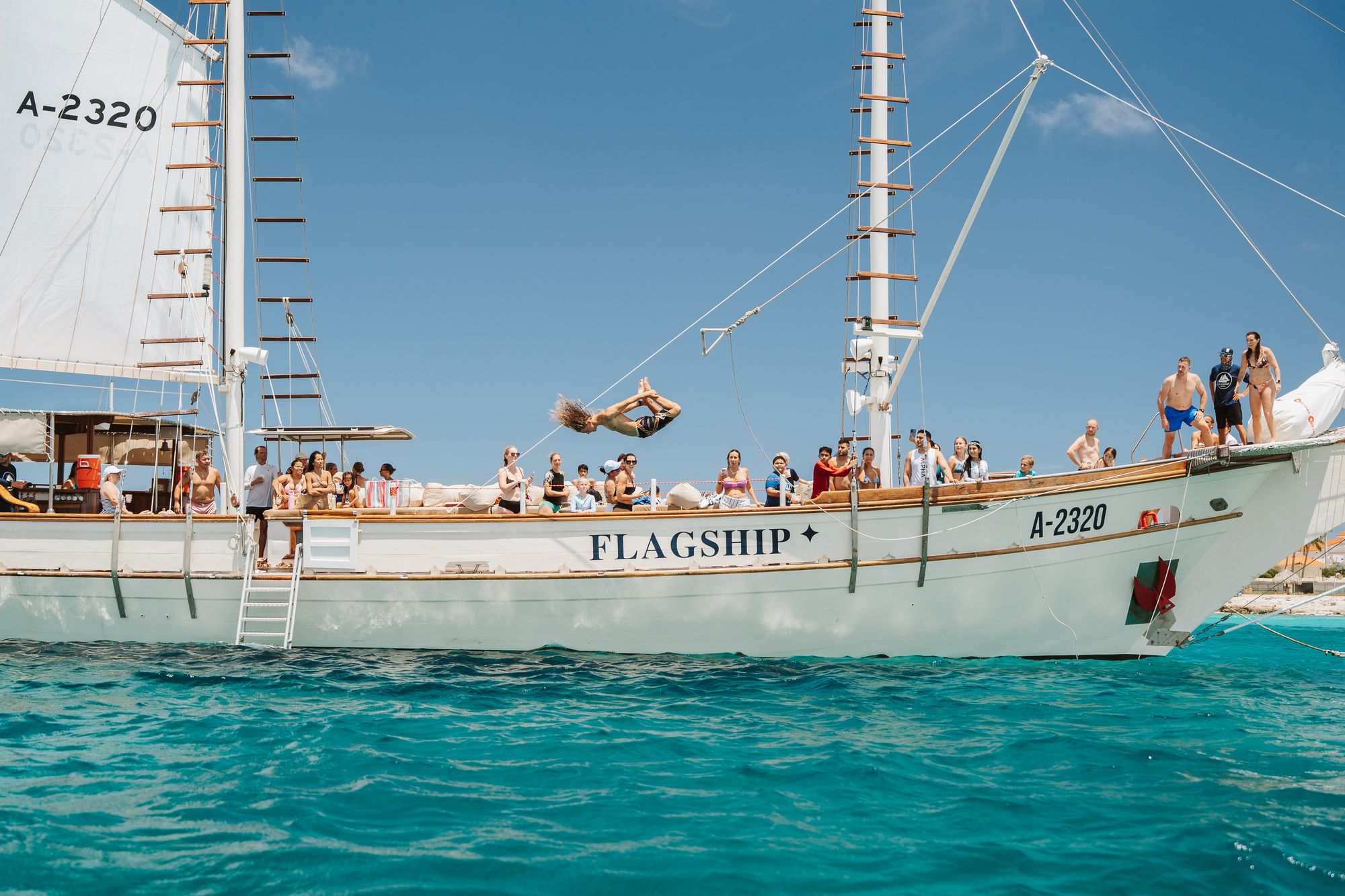 Guest doing a backflip off the rope swing on the Flagship into turquoise water