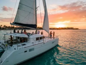 Luxury catamaran sailing through turquoise Caribbean waters at sunset in Aruba with passengers enjoying golden hour cruise