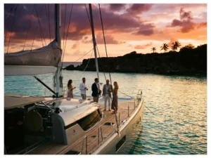 Luxury catamaran anchored in turquoise Caribbean waters at sunset with passengers on deck, Aruba coastline in background